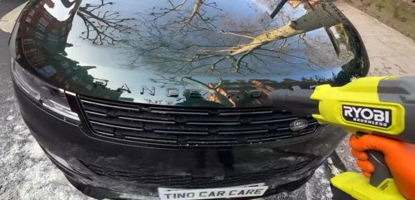 Detailer using a blower to dry a car after washing