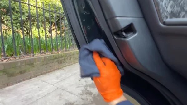 Drying a vehicle door panel with a clean microfiber cloth