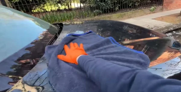Hand drying a freshly washed car with a microfiber cloth in Oakland